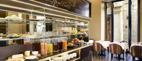 A buffet area with various food items, beverages, and a seating area with tables and chairs.