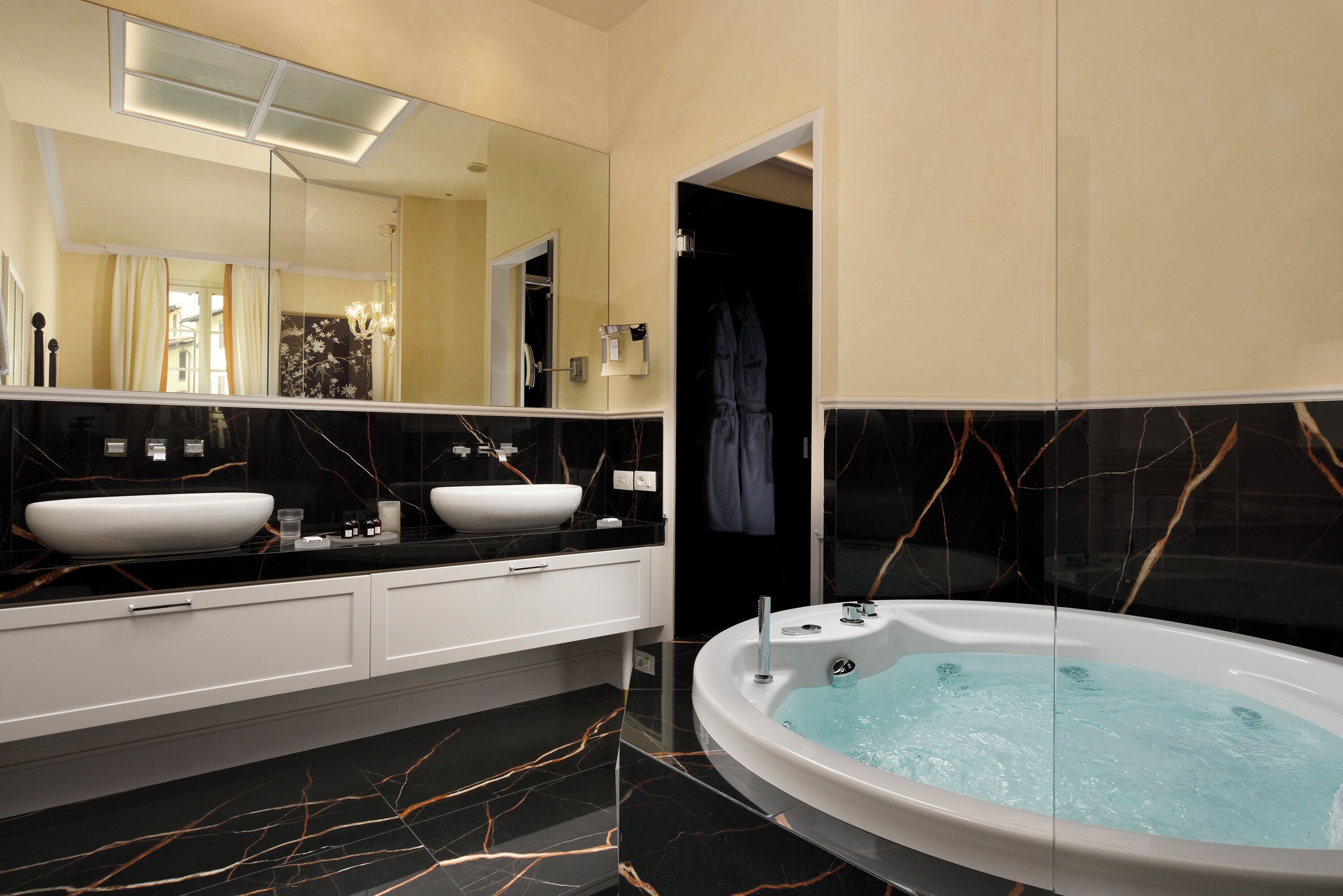 Un baño moderno con un espejo grande, dos lavamanos, una bañera y una ducha a ras de suelo.