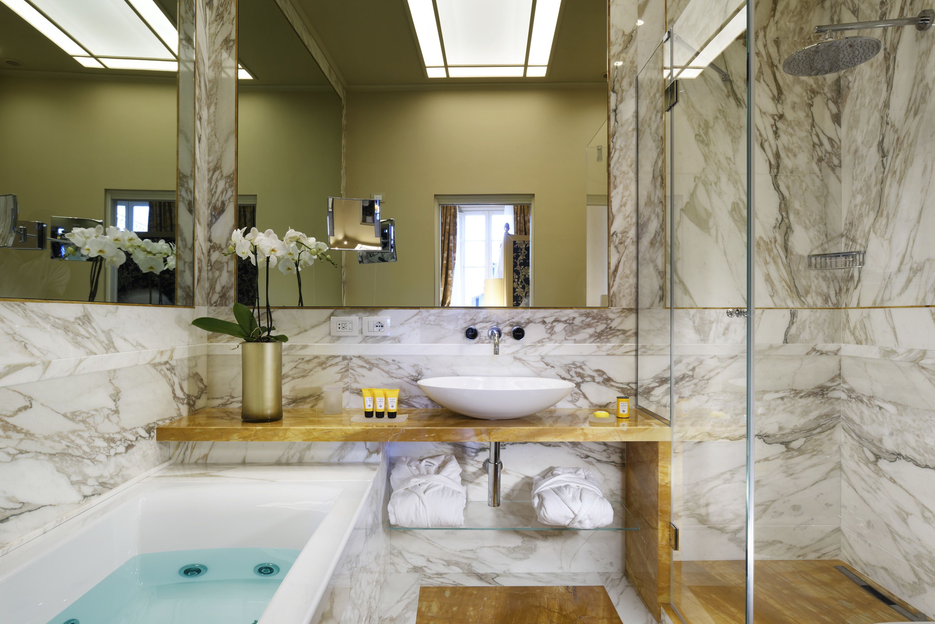 Un baño moderno con un lavabo de mármol, una bañera y una ducha con mampara de vidrio.
