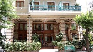 Ein Hotel Eingang mit einem Schild mit der Aufschrift 'HOTEL KATERINA', einem überdachten Eingangsbereich und einem Balkon mit blauen Geländern.