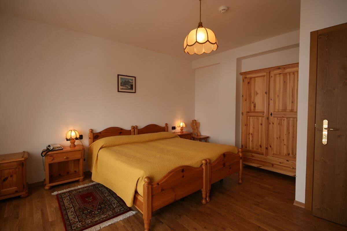 A bedroom with a wooden bed, bedside lamps, a rug, and a wardrobe.