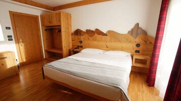 Quarto com estrutura de madeira, cama, guarda-roupa de madeira e cabeceira com tema de montanha.
