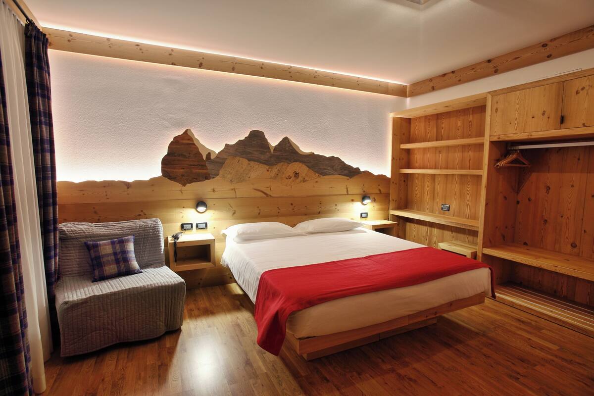 A bedroom with a wooden bed, a nightstand, a chair, and a wardrobe.