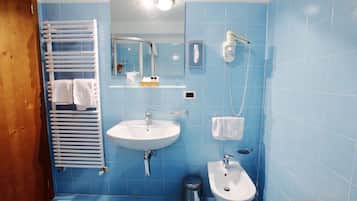 A bathroom with a sink, bidet, and towel rack.