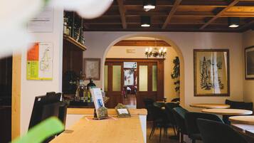 Un interior de restaurante con mostrador de madera, sillas negras y un candelabro.