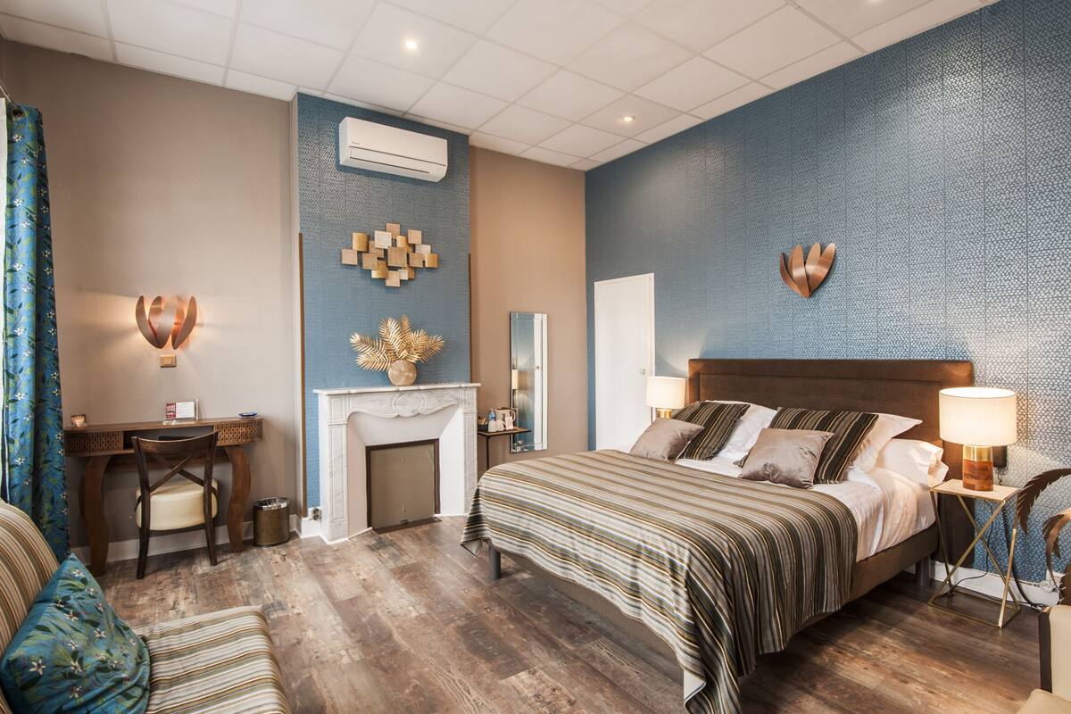 Quarto de hotel moderno com uma cama grande, uma escrivaninha e lareira.