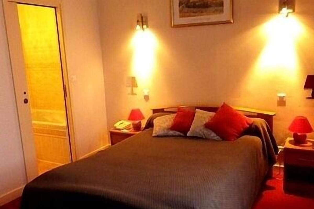 Een hotelkamer met een bed, twee nachtkastjes en twee wandlampen.