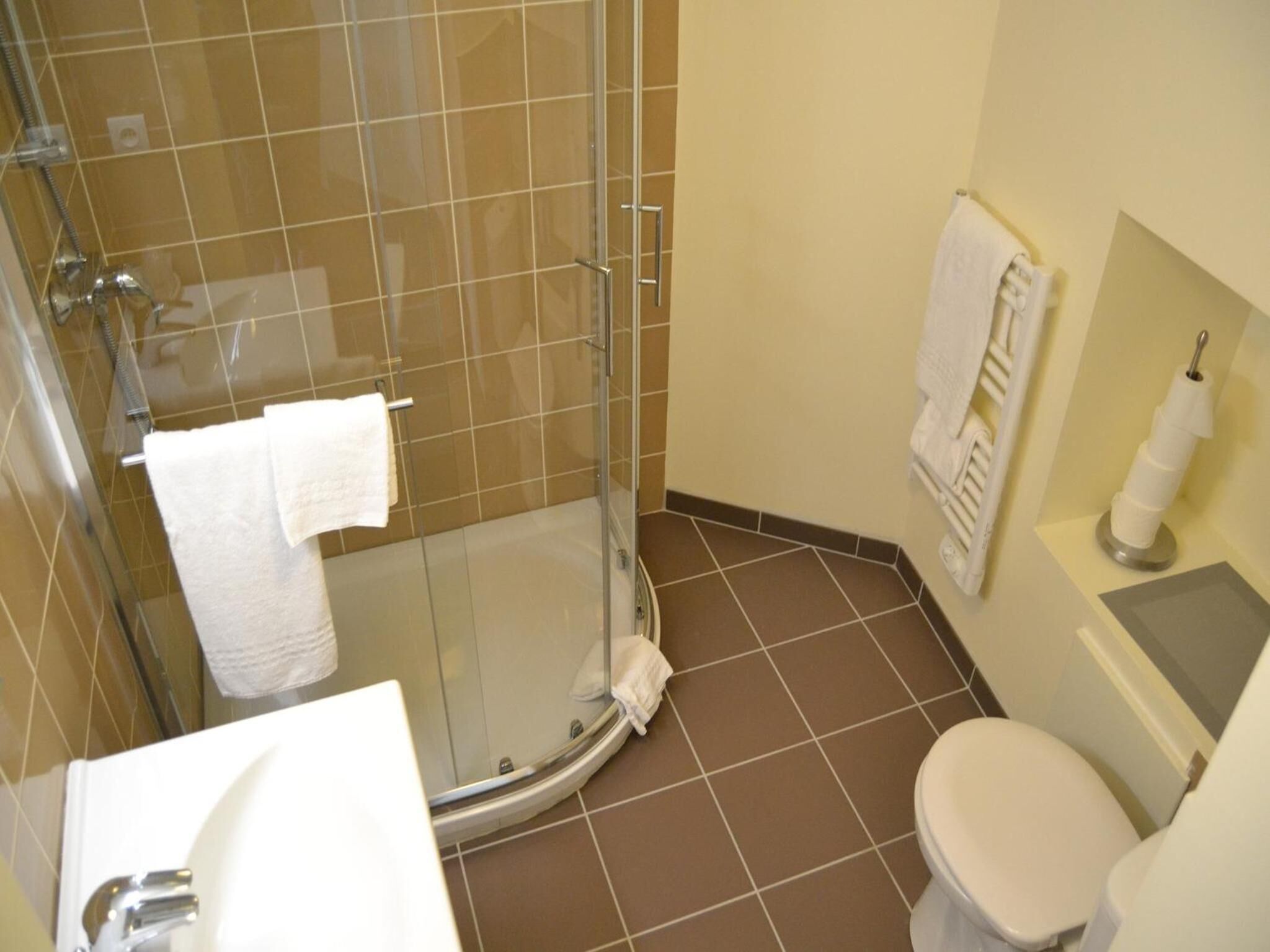 A bathroom with a glass-enclosed shower, a toilet, and a sink.