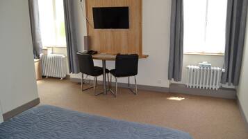Une chambre d’hôtel comprenant un lit, un bureau avec deux chaises, un téléviseur fixé au mur et un radiateur.