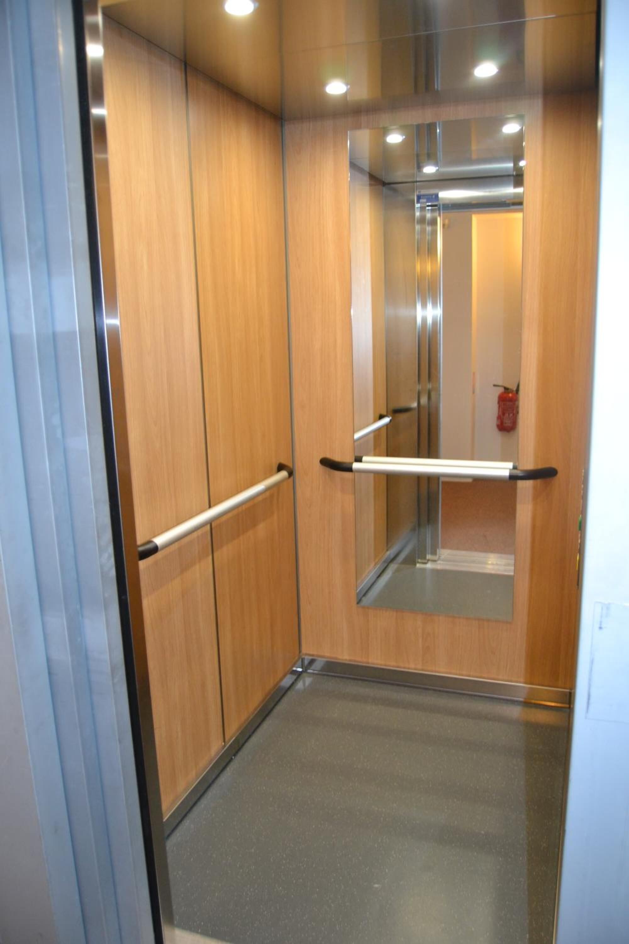 An elevator with wooden walls and a metal handrail.
