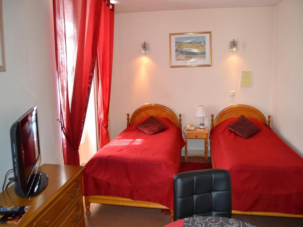 A room with two beds, a TV, a desk, and a chair.