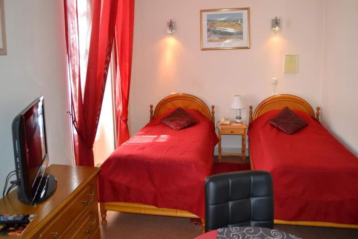 Een kamer met twee bedden, een televisie, een bureau en een stoel.