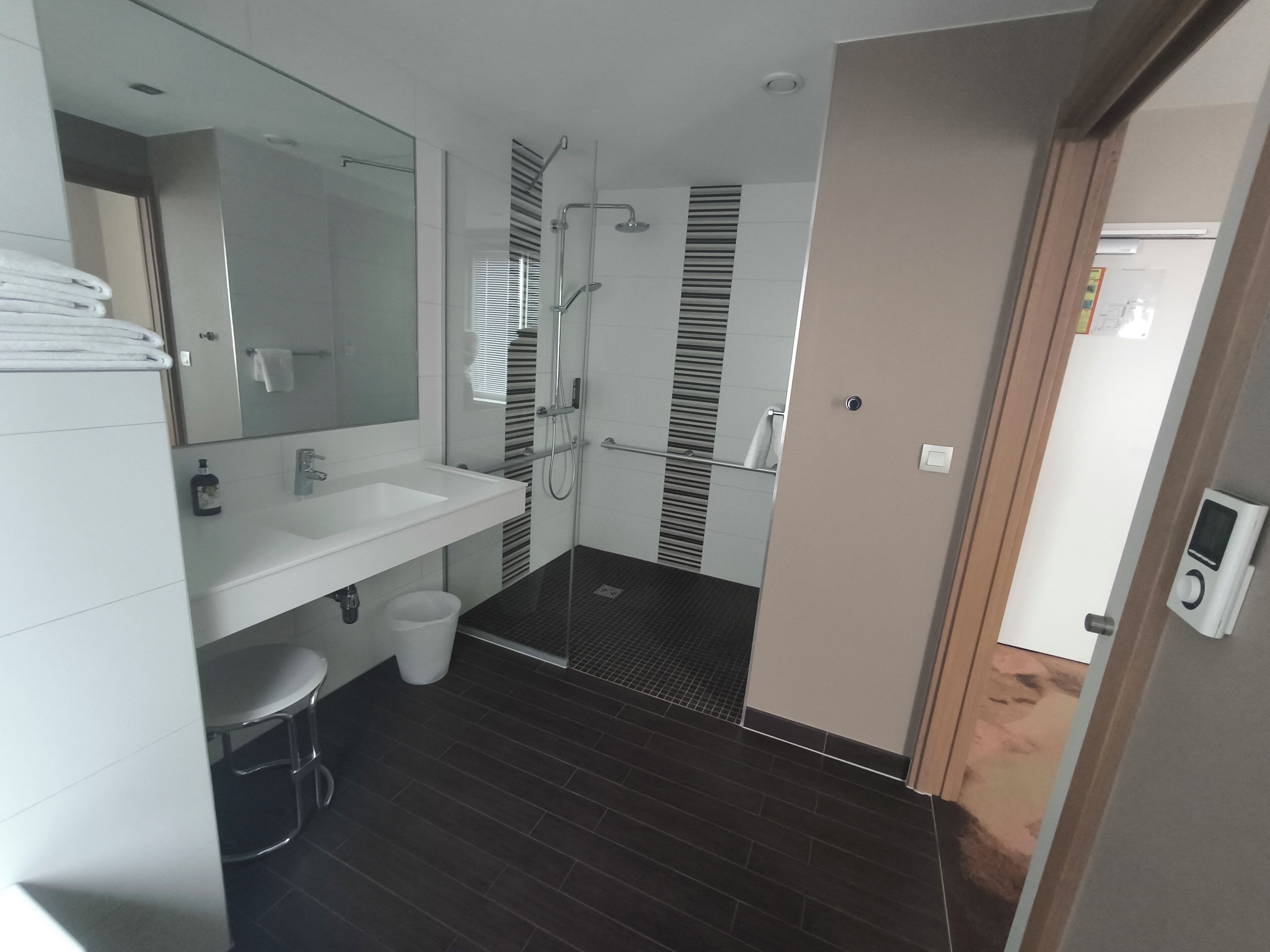 A modern bathroom with a white sink, mirror, and shower.