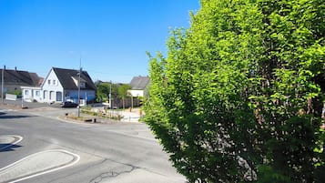 Eine Wohnstraße mit Häusern, blauem Himmel und einem Baum.