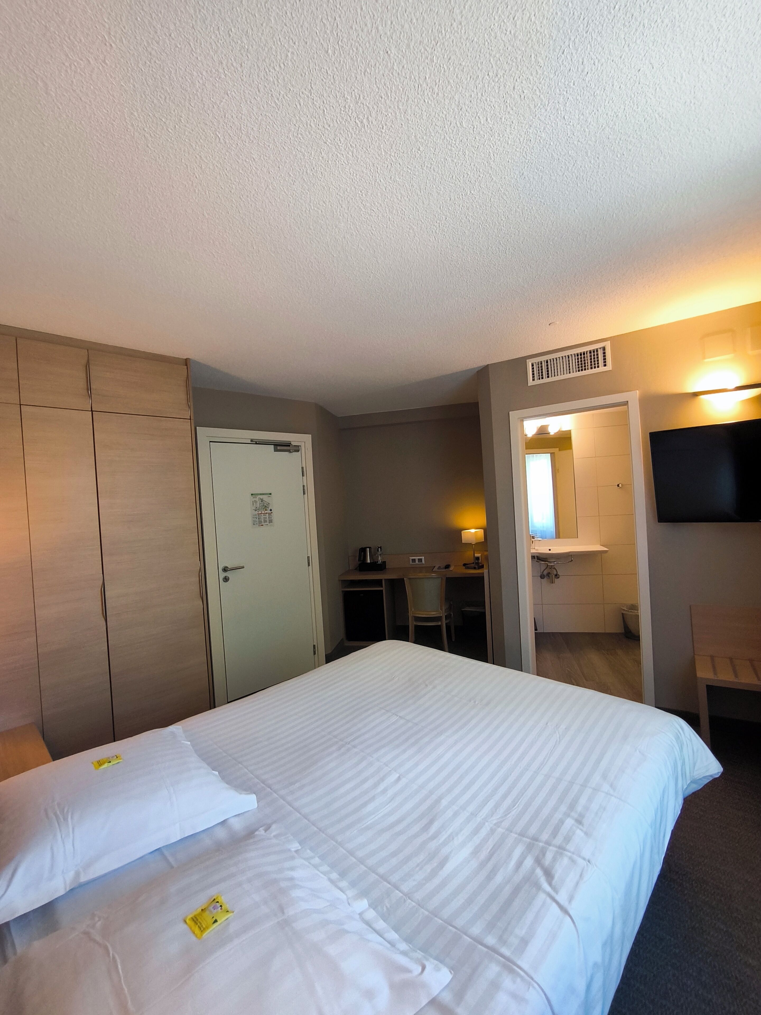 Une chambre d’hôtel comprenant un lit, un bureau, une chaise, une télévision et une salle de bain.