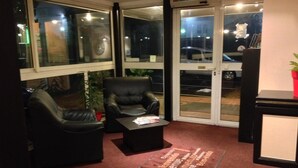 Un vestíbulo de hotel con sillones de cuero, una mesa de centro y un tapete de bienvenida.