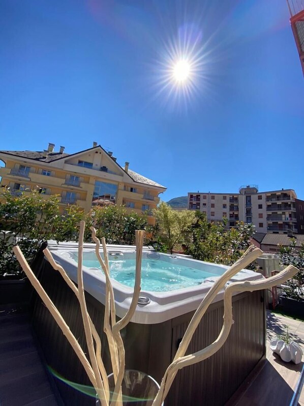 A hot tub on a rooftop with a clear blue sky and buildings in the background. - Eurossola (Domodossola)