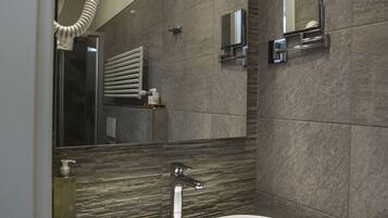 A modern bathroom with a large oval sink, a mirror, and a towel rack.