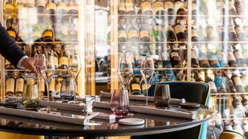 A restaurant table set with wine glasses and bottles, with a person serving.