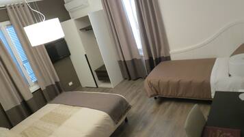 Ein Hotelzimmer mit zwei Betten, einem Fernseher und einem Schreibtisch.