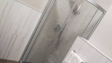 Une salle de bain avec une douche à parois de verre, un lavabo blanc et un porte-serviettes.