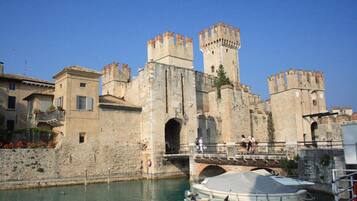Un château historique en pierre, doté d’un fossé, d’un pont et de bateaux amarrés dans l’eau.