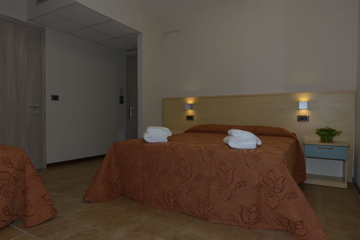 Une chambre d’hôtel avec un lit, une table de chevet et une porte.