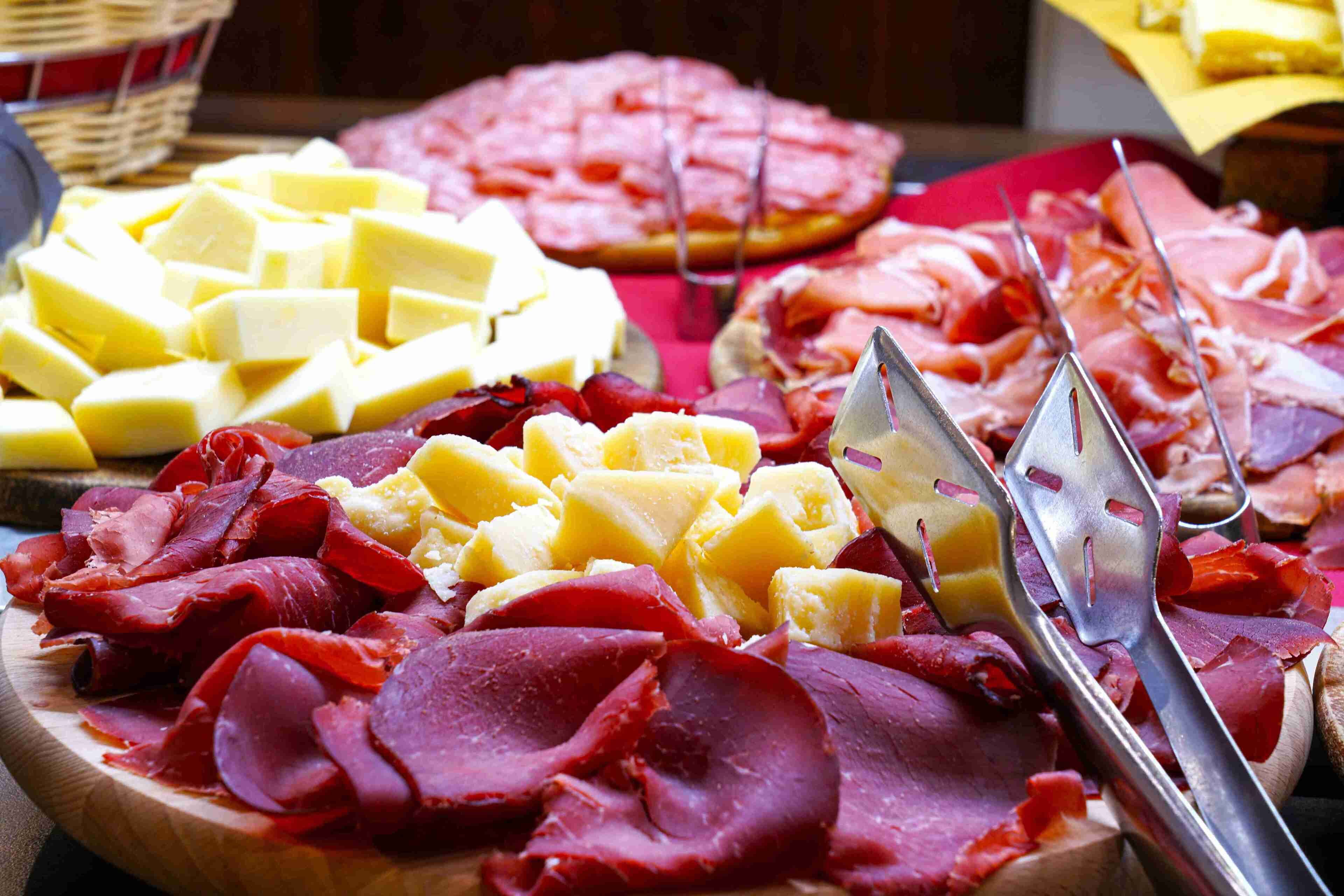 A wooden board with various types of cheese and cured meats.