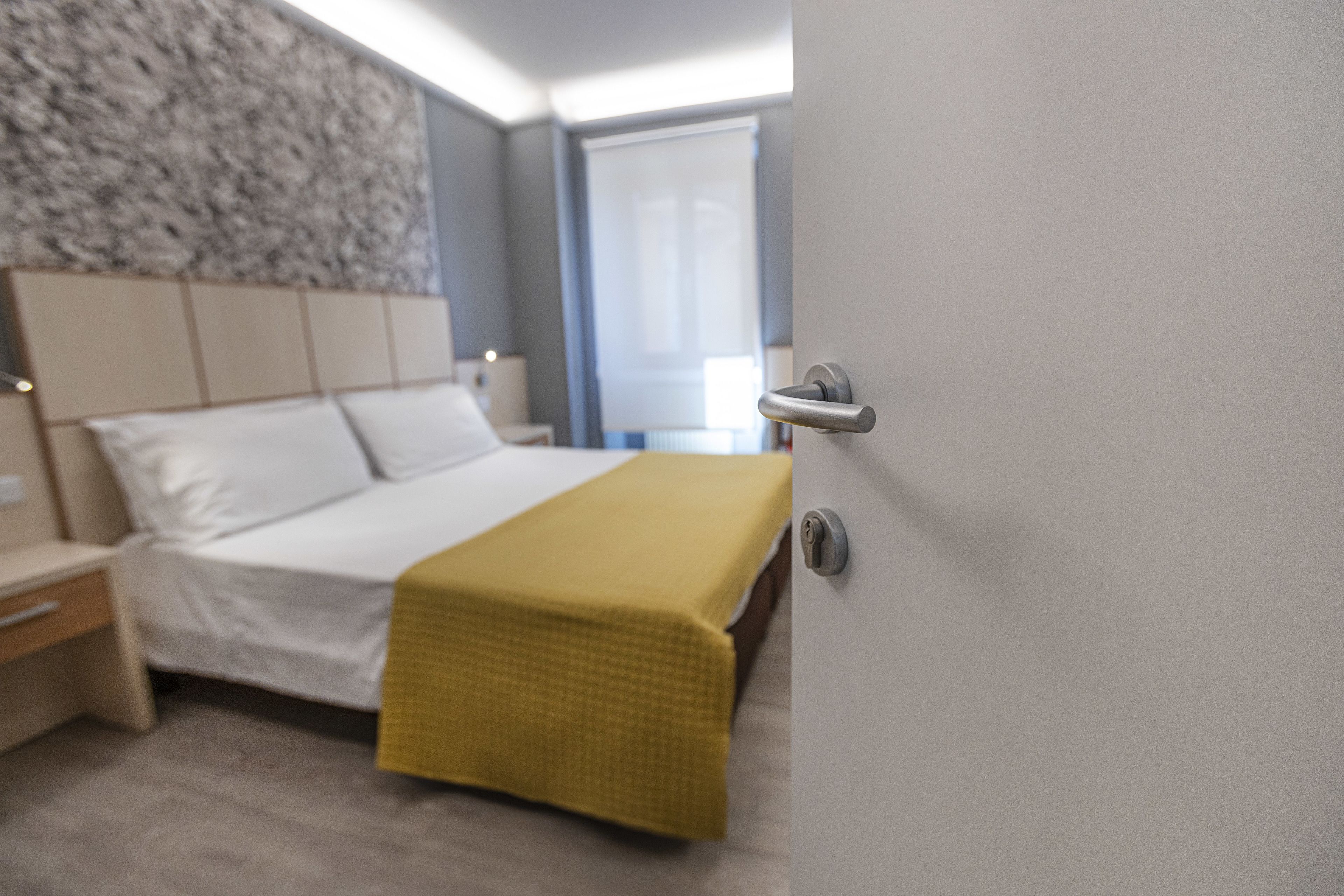 Ein modernes Hotelzimmer mit Bett, Nachttisch und einem fensterbepflanzten Fenster.