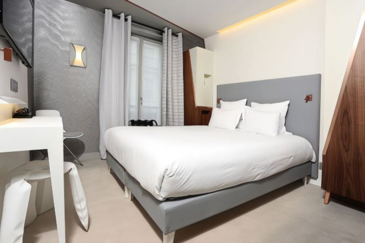 A modern bedroom with a bed, a desk, and a chair.