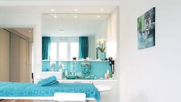 Relax in a serene space with a neatly made bed, large mirror, and wall-mounted phone.