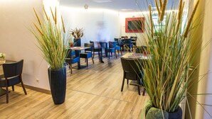 A modern interior with wooden flooring, blue chairs, and large potted plants. - Hotel Volapük (Konstanz)