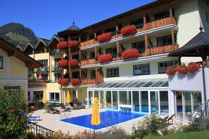 Una piscina techada, una piscina al aire libre, sombrillas