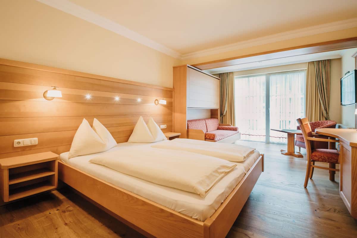 Una habitación de hotel con una cama de madera, mesitas de noche, un escritorio y una silla.
