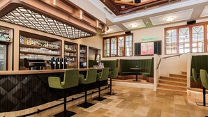 Una zona de bar con mostrador, taburetes y un área de estar con una escalera.