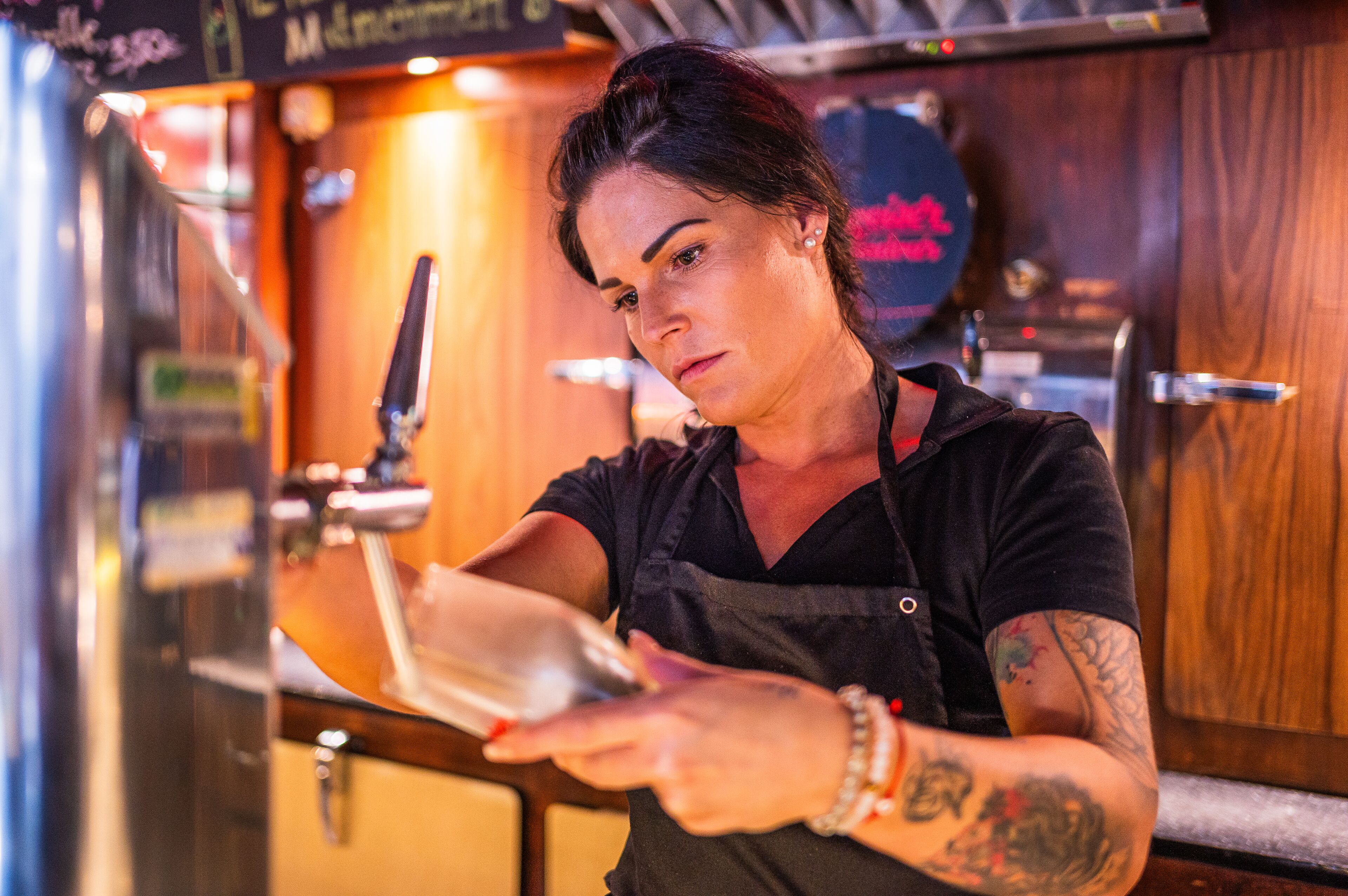 A person pouring a drink from a tap into a glass.