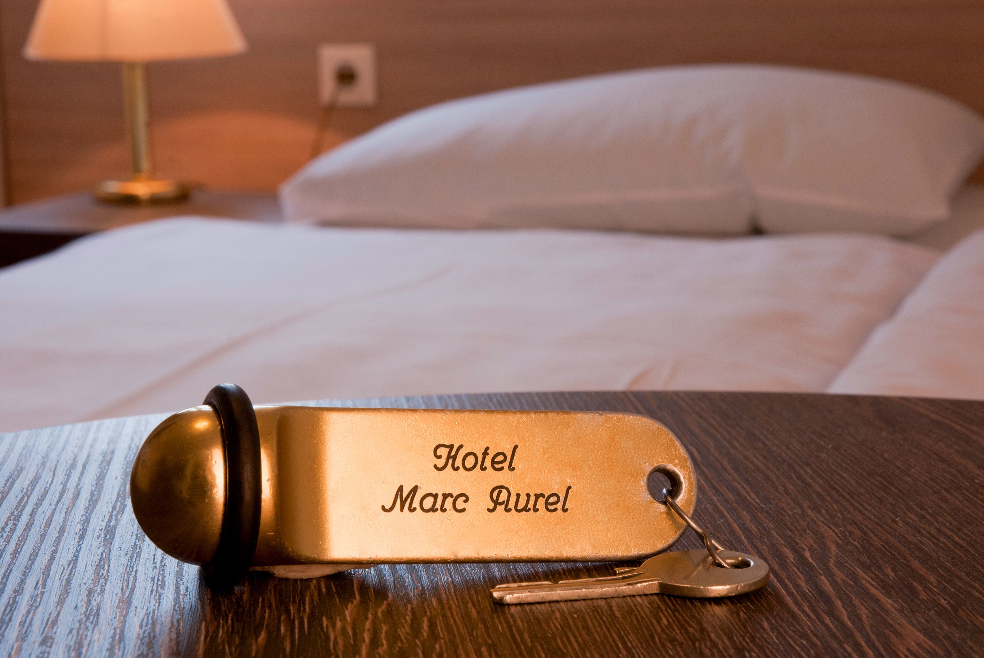 Ein Schlüsselanhänger mit der Gravur "Hotel Marc Purel", platziert auf einer Holzfläche.