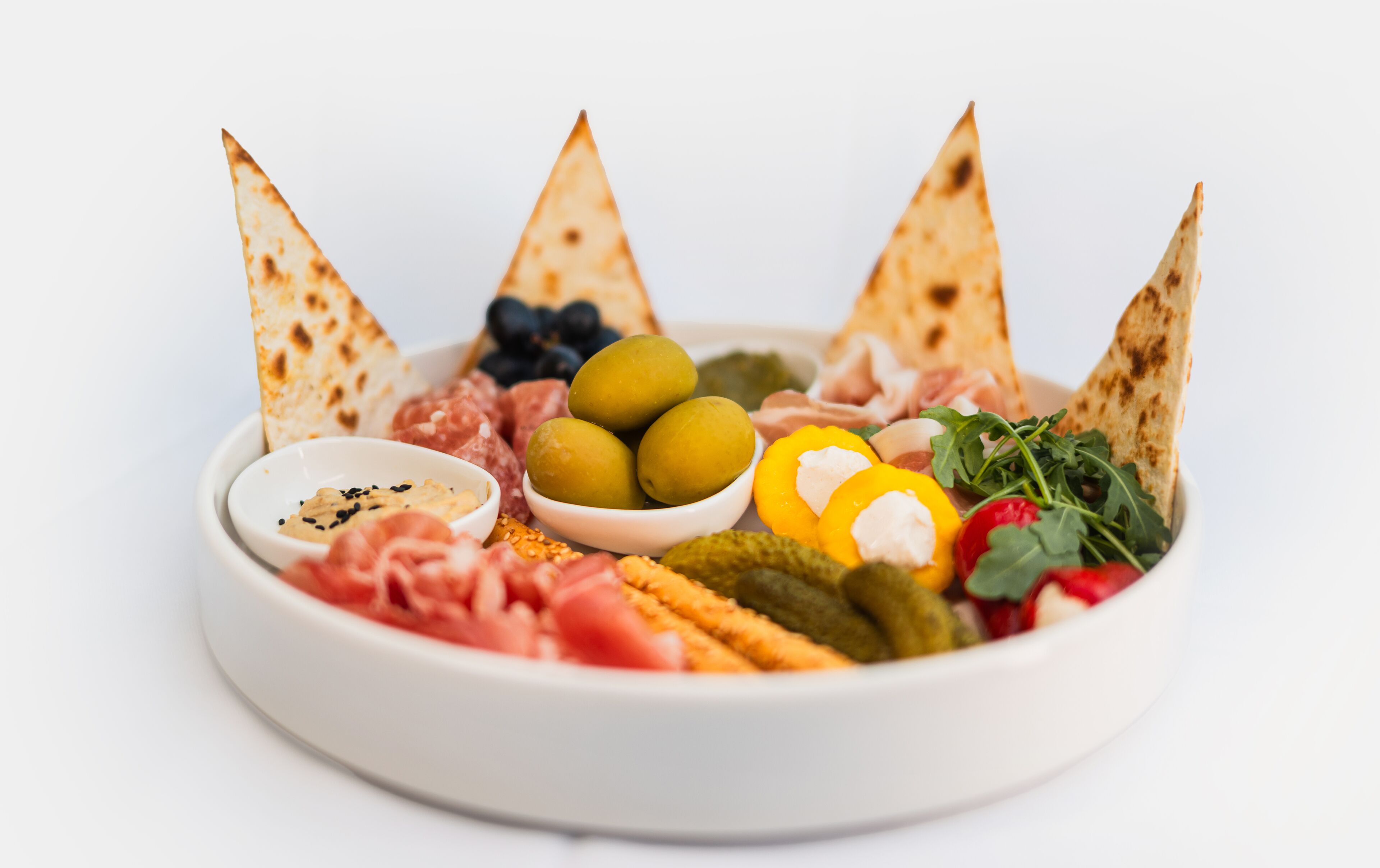 A charcuterie board with various meats, cheeses, olives, and pickles.
