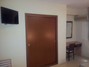 Comfortable room with a flat-screen TV, desk, and air conditioning unit.