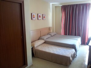 A hotel room with two beds, a wooden door, a headboard, and a curtain. - Primavera (Benidorm)