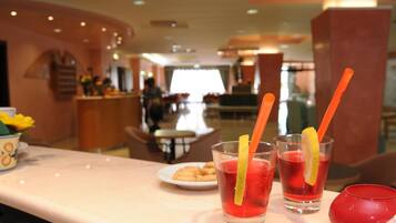 A hotel lobby with a reception desk, seating area, and a counter with a plate of cookies.