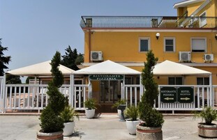 Un edificio amarillo con letrero de restaurante y recepción de hotel.