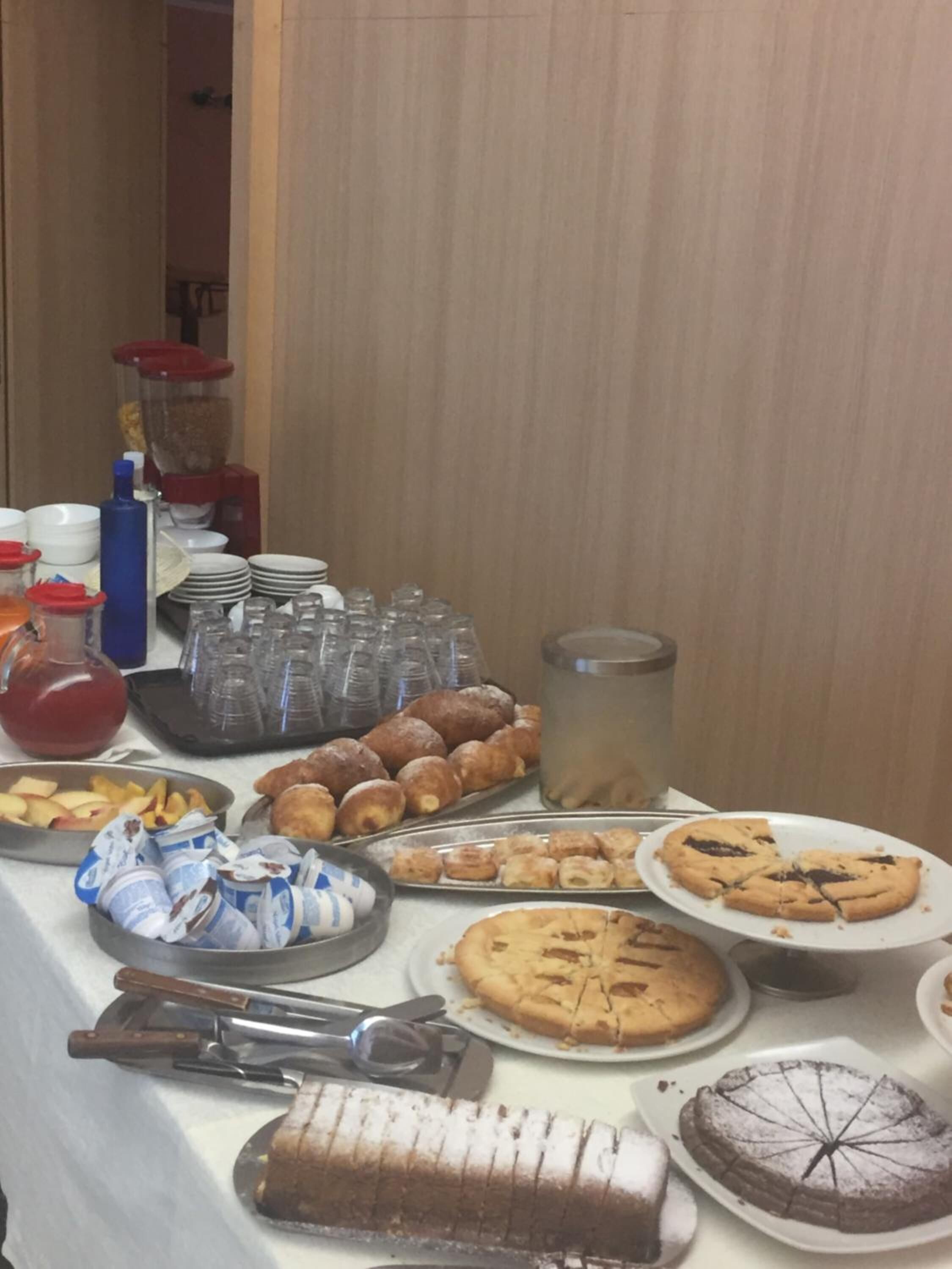 A buffet table with various food items including pastries, cookies, and a cake.