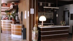 A reception area with a wooden reception desk, a patterned floor, and a decorative vase. - Hotel Harmony (Tortora)