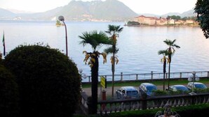 A waterfront view with palm trees, a fountain, and parked cars. - Hotel Villa Ruscello (Baveno)