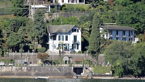 A hotel with a white facade, multiple windows, and a balcony. - Hotel Villa Ruscello (Baveno)