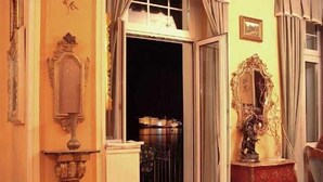 A room with a large mirror, a wooden cabinet, and a view of a balcony with a railing. - Hotel Villa Ruscello (Baveno)