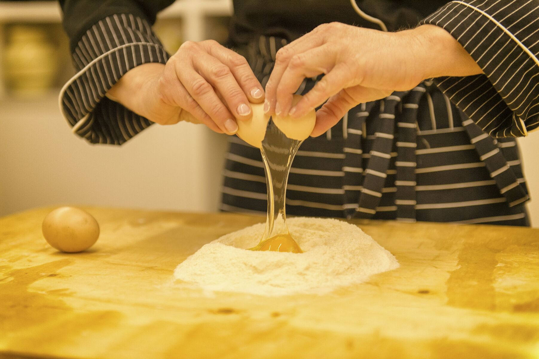 A person preparing food, specifically mixing ingredients on a wooden surface.