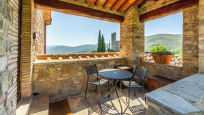 Un patio de piedra con una mesa y sillas, vista al campo y techo de madera.