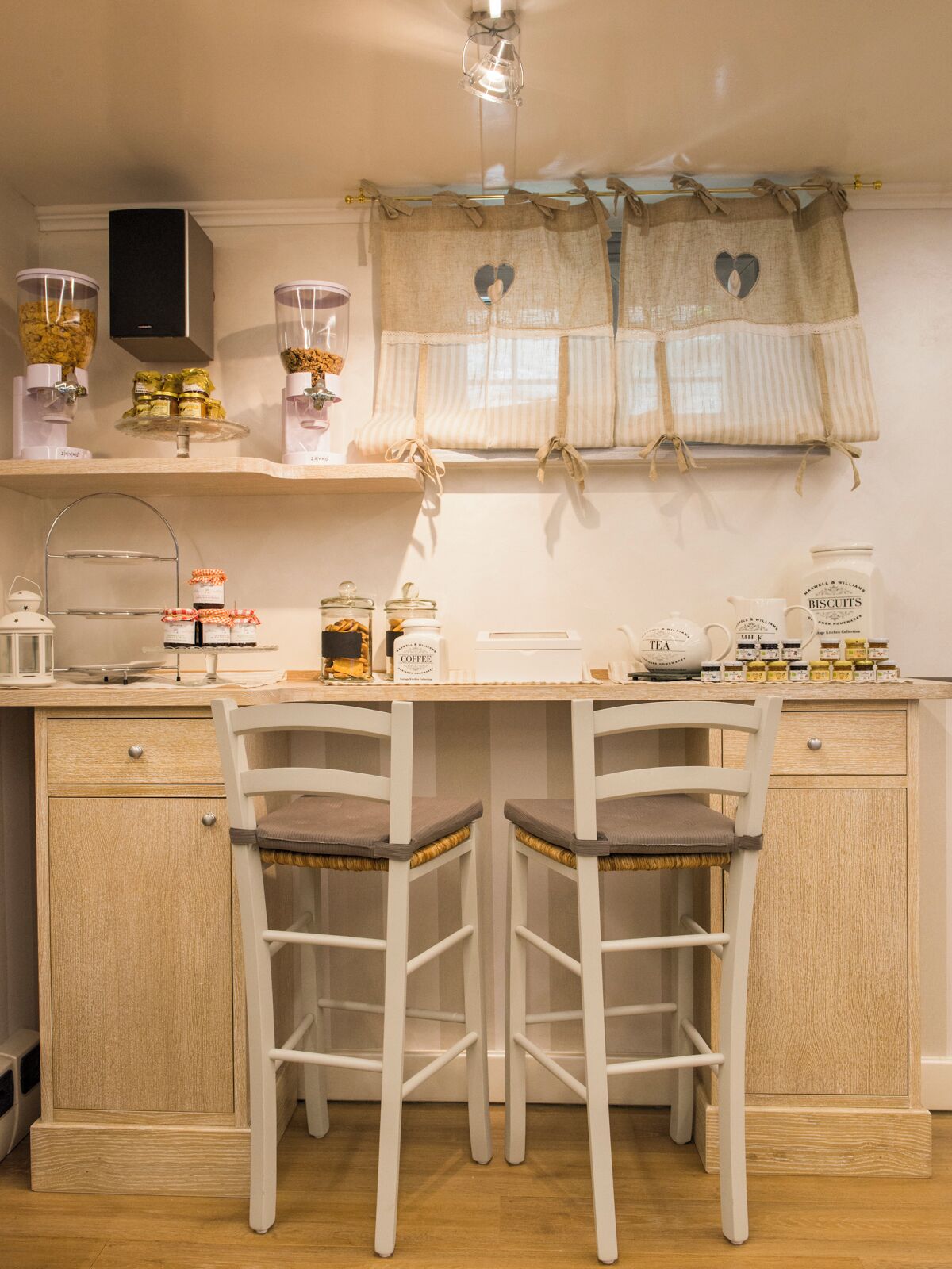 Cozinha com duas cadeiras brancas, bancada de madeira e diversos potes e recipientes.